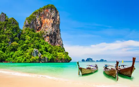 Klong Nin Beach med turkost vatten, vita stränder, grönskande klippor och traditionella longtailbåtar. En idyllisk thailändsk dröm.