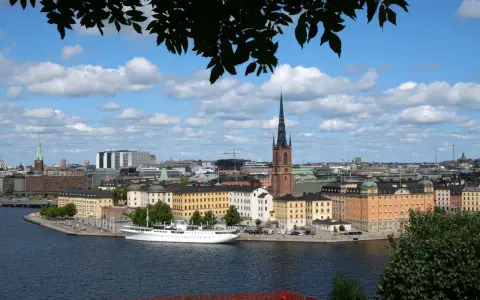 Vy över Riddarfjärden med en vit båt vid kajen, omgiven av Stockholms vackra byggnader. Perfekt för annorlunda utflykter i Stockholm.