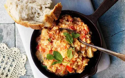 En smak av cypern mat: äggröra med tomat och örter i en gjutjärnspanna, serverad med ett gott bröd.