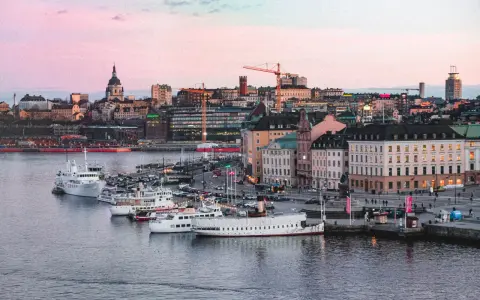 Stockholms silhuett med fartyg i hamnen vid solnedgången. En perfekt vy för att uppleva Stockholm.