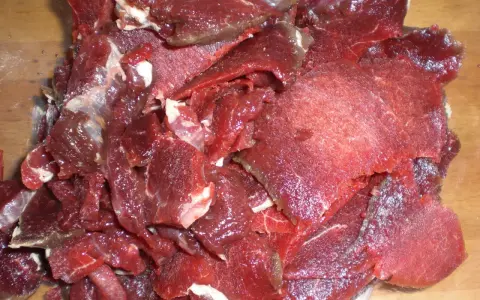 Råa, tunt skurna bitar av mörkrött kött, redo för ett läckert souvas recept.