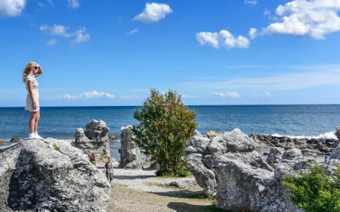 Flicka spanar ut över havet vid raukarna på Gotland. Bra tips för en solig dag!