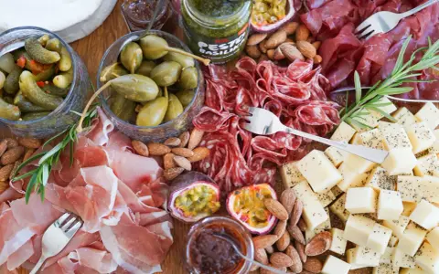 En härlig ost och charkbricka med salami, prosciutto, osttärningar, kapris, cornichoner, nötter och passionsfrukt.