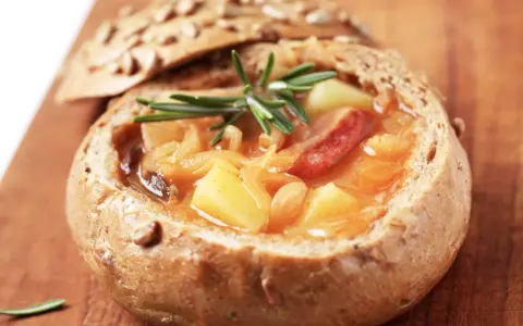 En mustig gryta med potatis och korv serveras i ett urgröpt bröd, en härlig tjeckisk matupplevelse.