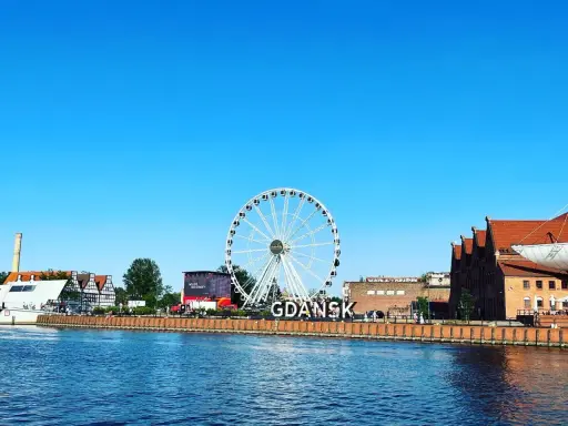 Stadsvy över Gdansk, Polen, med ett stort pariserhjul och byggnader längs floden.