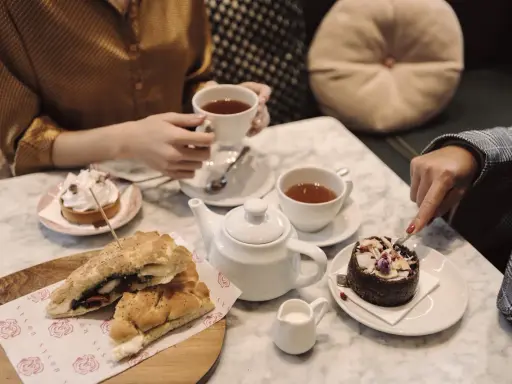Två personer njuter av afternoon tea i Stockholm med smörgåsar och bakelser.