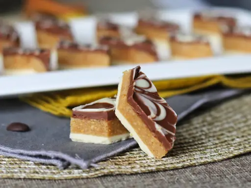 Två bitar av marockansk mat, en chokladkaka med lager av nougat och vit choklad, dekorerad med virvlar av vit och mörk choklad.