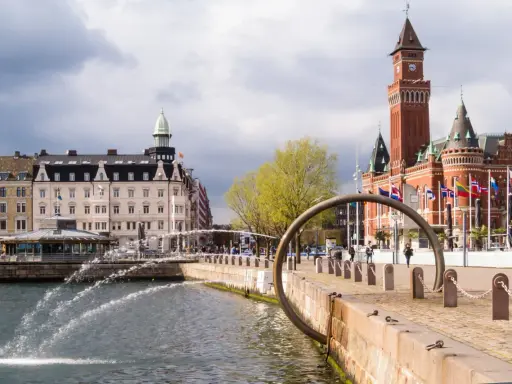 Vattenfontäner vid hamnen i Helsingborg, med Rådhuset i bakgrunden. Perfekt för en promenad bland sevärdheter.