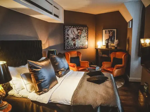 Ett lyxigt rum på Lydmar hotell med en stor säng, två orangea fåtöljer och konst på väggarna.