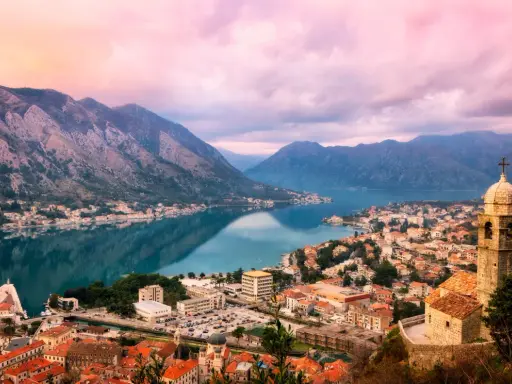 Vacker vy över Kotorbukten i Montenegro. En stad med röda tak och en kyrka vid vattnet, omgiven av berg. En perfekt plats för montenegro mat.
