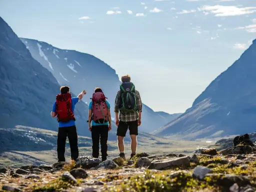 Två vandrare med ryggsäckar blickar ut över en dal under en kungsleden vandring. En pekar mot bergen.