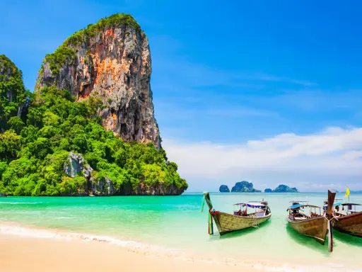 Klong Nin Beach med turkost vatten, vita stränder, grönskande klippor och traditionella longtailbåtar. En idyllisk thailändsk dröm.
