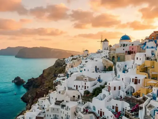 Vacker solnedgång över Oia, Santorini. Vita hus klättrar längs klippan ner mot det turkosblå havet. En dröm om en resa till Grekland.