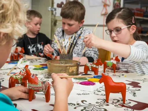Barn målar röda Dalahästar, en klassisk syn att se i Mora.
