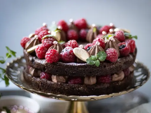 En lyxig kladdkaka med fluffig chokladmousse, toppad med färska hallon, mynta och guldkulor. Perfekt för en speciell fikastund.