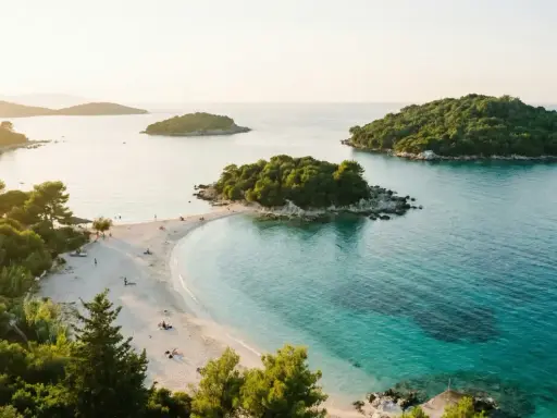 Vacker strand med turkost vatten och gröna öar. Perfekt för en resa till Albanien med tips om sol och bad.
