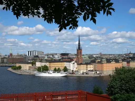 Vy över Riddarfjärden med en vit båt vid kajen, omgiven av Stockholms vackra byggnader. Perfekt för annorlunda utflykter i Stockholm.