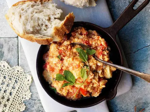En smak av cypern mat: äggröra med tomat och örter i en gjutjärnspanna, serverad med ett gott bröd.