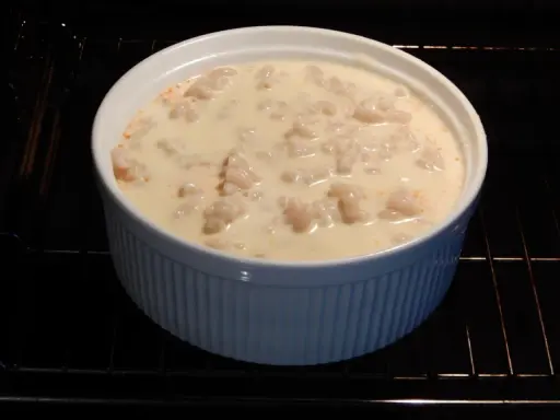 En vit ugnsform med makaroner i en krämig sås, redo för ett läckert pastitio recept.