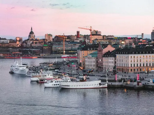 Stockholms silhuett med fartyg i hamnen vid solnedgången. En perfekt vy för att uppleva Stockholm.