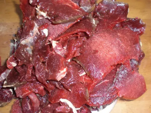 Råa, tunt skurna bitar av mörkrött kött, redo för ett läckert souvas recept.