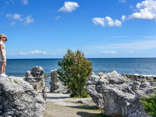 Flicka spanar ut över havet vid raukarna på Gotland. Bra tips för en solig dag!