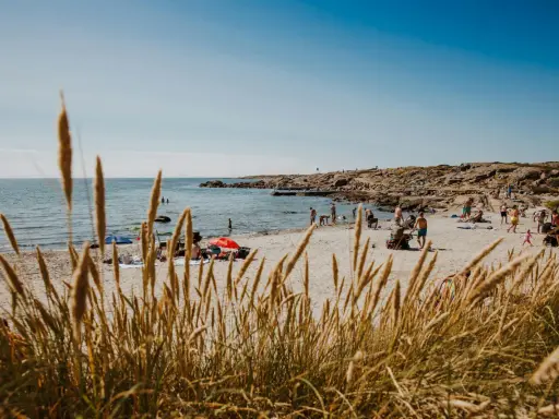 En solig stranddag i Halland med folk som badar och solar. Ett perfekt utflyktsmål för hela familjen.
