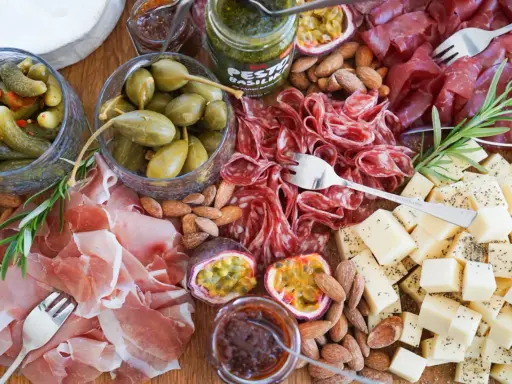En härlig ost och charkbricka med salami, prosciutto, osttärningar, kapris, cornichoner, nötter och passionsfrukt.