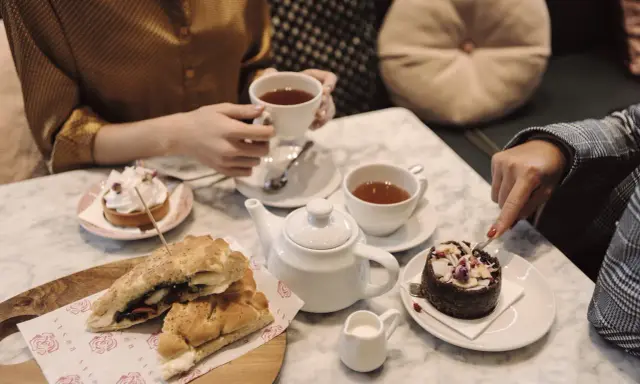 Två personer njuter av afternoon tea i Stockholm med smörgåsar och bakelser.