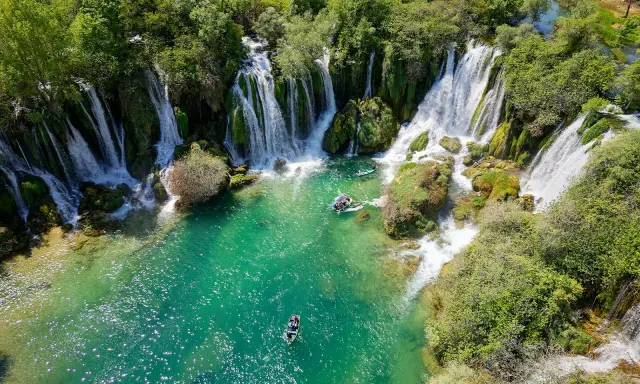 Vackra Kravice vattenfall med turkost vatten och båtar som glider fram. En idyllisk plats för avkoppling.