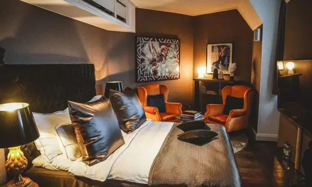 Ett lyxigt rum på Lydmar hotell med en stor säng, två orangea fåtöljer och konst på väggarna.