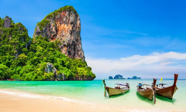 Klong Nin Beach med turkost vatten, vita stränder, grönskande klippor och traditionella longtailbåtar. En idyllisk thailändsk dröm.