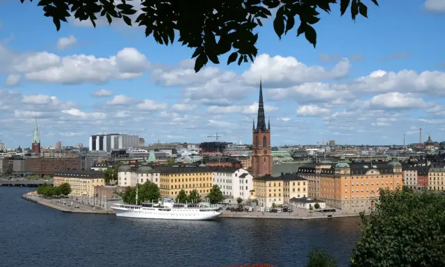 Vy över Riddarfjärden med en vit båt vid kajen, omgiven av Stockholms vackra byggnader. Perfekt för annorlunda utflykter i Stockholm.