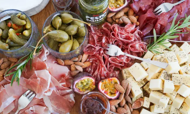 En härlig ost och charkbricka med salami, prosciutto, osttärningar, kapris, cornichoner, nötter och passionsfrukt.