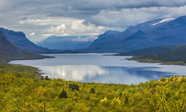 Vacker sjö omgiven av höstfärgad skog och berg. Perfekt för vandring dagsturer Sverige.