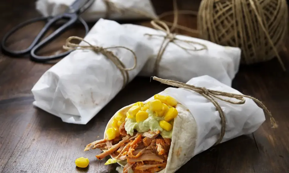 En läcker pulled pork wrap med majs och avokadokräm, inslagen i papper och bunden med snöre.