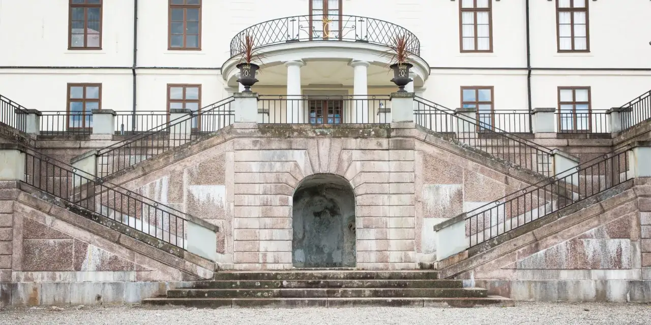 Imponerande trappa leder upp till ett slott i Sverige. Tänk dig att bo på slott i Sverige och få kliva ut på denna balkong!