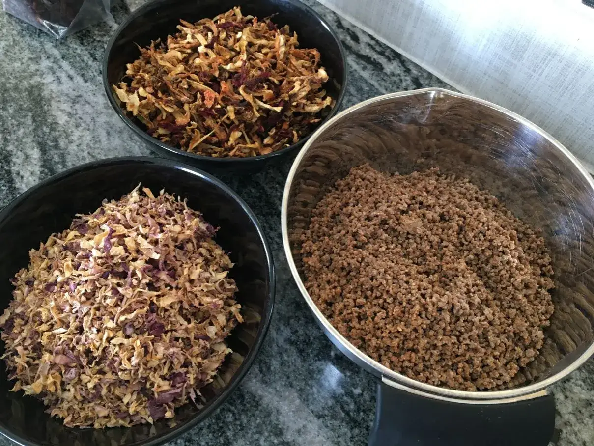 Tre skålar med torkad mat: en med köttfärs, en med torkad lök och en med torkade grönsaker.