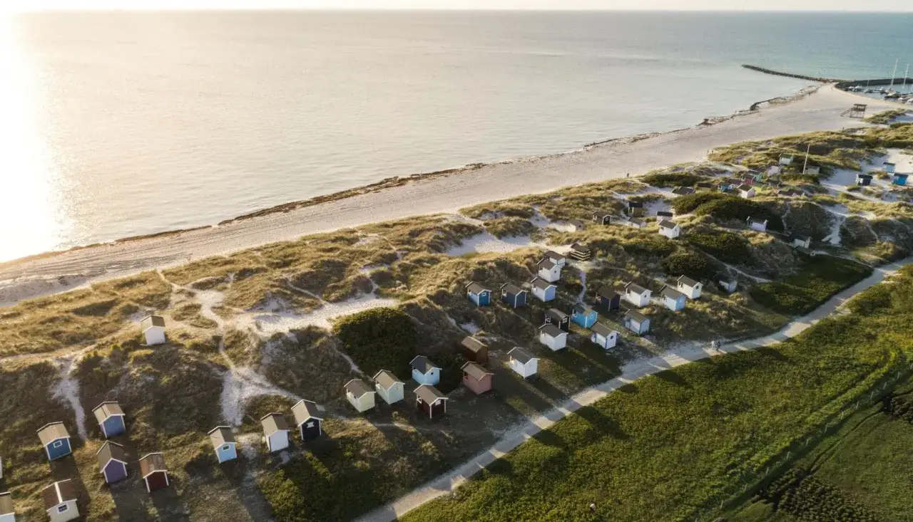 Färggranna små stugor längs en sandstrand i Skåne, perfekta för avkoppling och aktiviteter för vuxna.