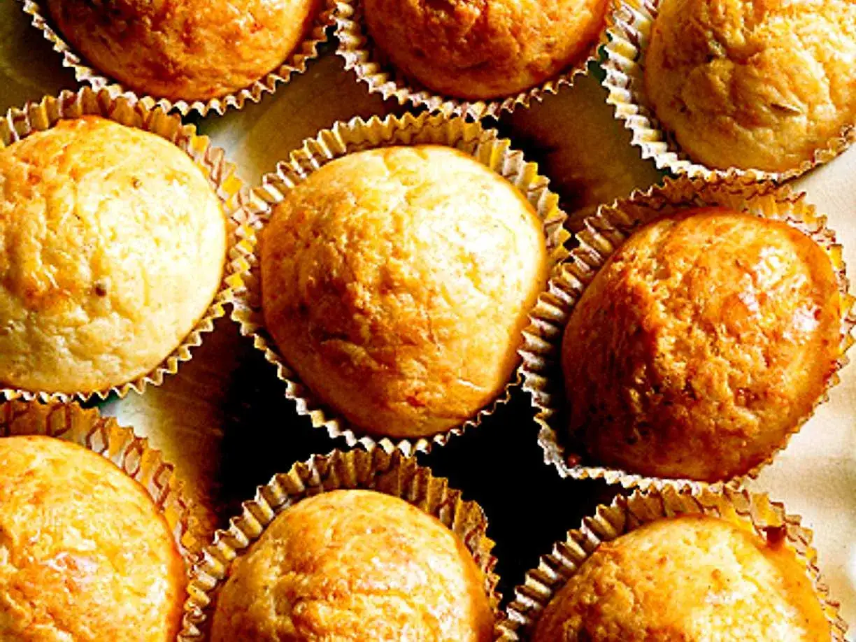 Flera gyllene matmuffins med ost i sina pappersformar, redo att avnjutas.