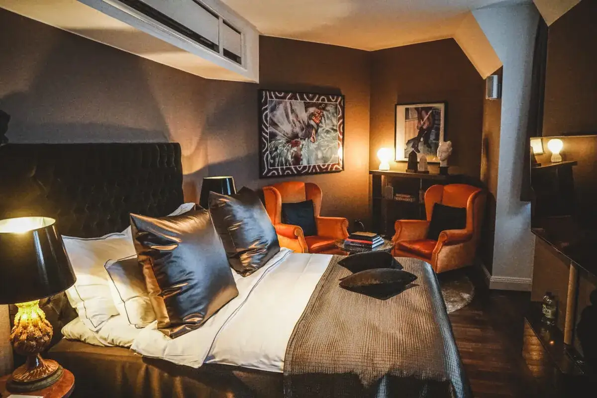 Ett lyxigt sovrum på Lydmar Hotel med en stor säng, orange fåtöljer och konst på väggarna.