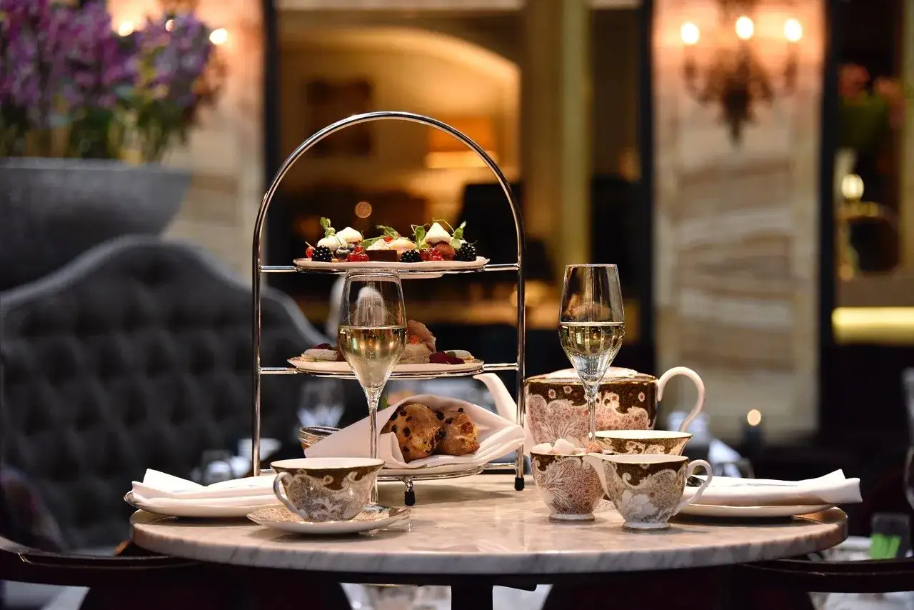Ett elegant afternoon tea på Grand Hotel med tårtfat, glas med bubbel och vackert porslin.