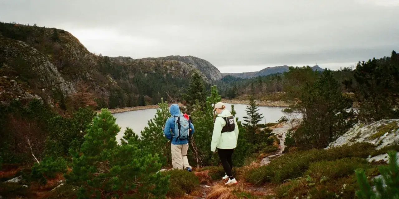 Två personer vandrar i ett bergigt landskap med en sjö. En perfekt sommardag för vandring i Sverige.