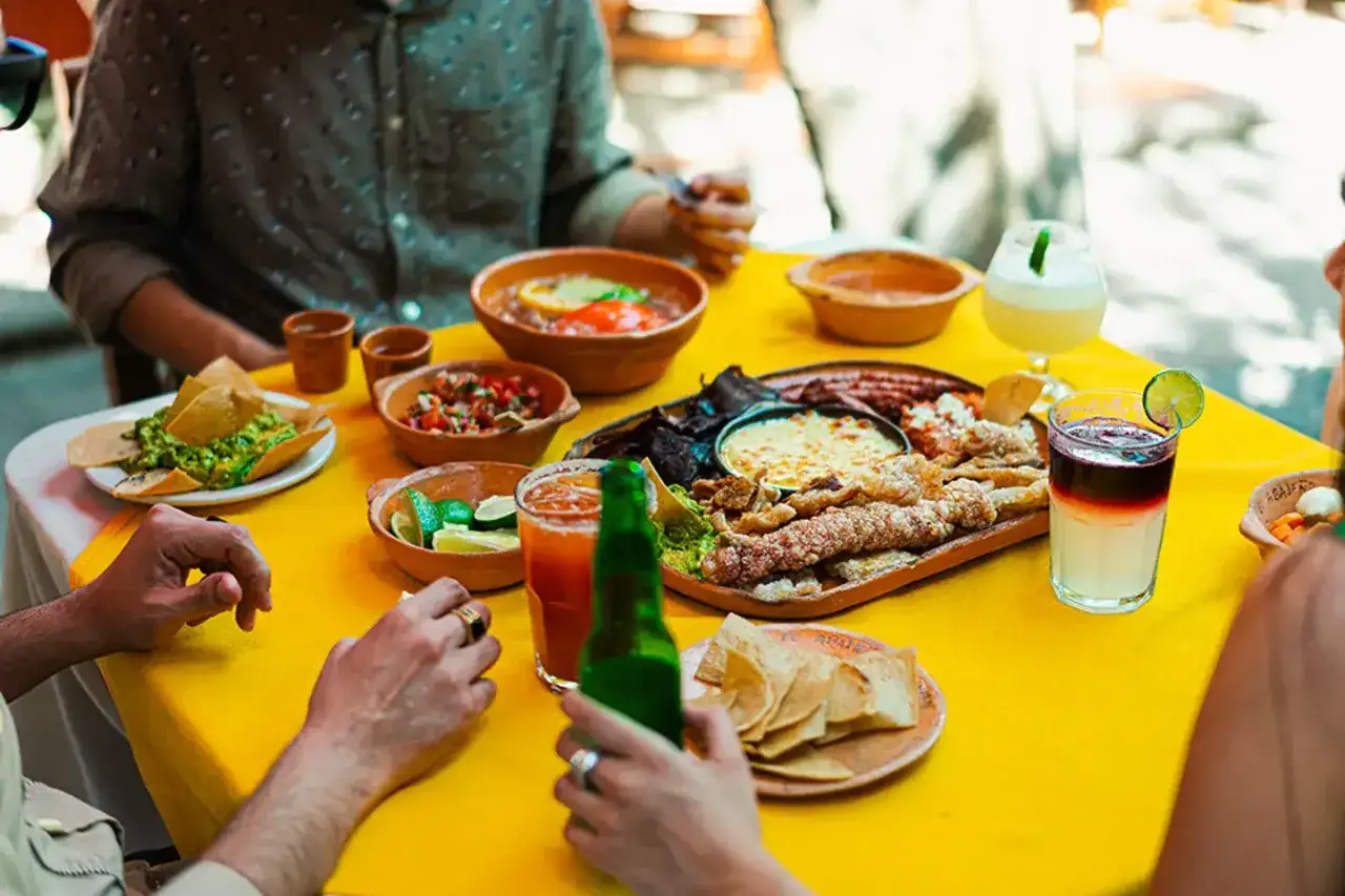 En härlig måltid med mexikansk mat, inklusive guacamole, salsa, nachos och olika kötträtter, serveras på ett gult dukbord.
