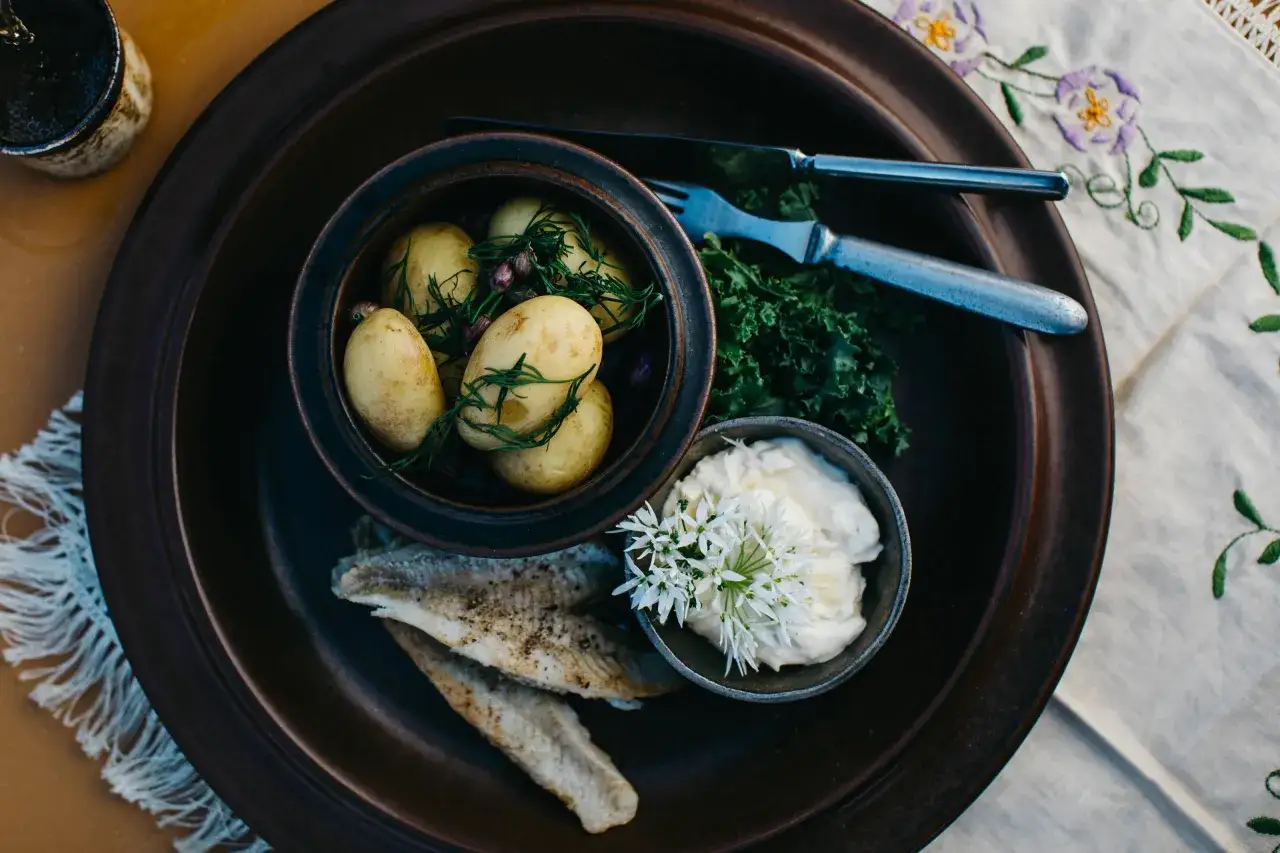 En rustik tallrik med nykokta potatisar, stekt fisk och en kr&auml;mig dipp. En smak av finsk mat, perfekt f&ouml;r en sommarkv&auml;ll.
