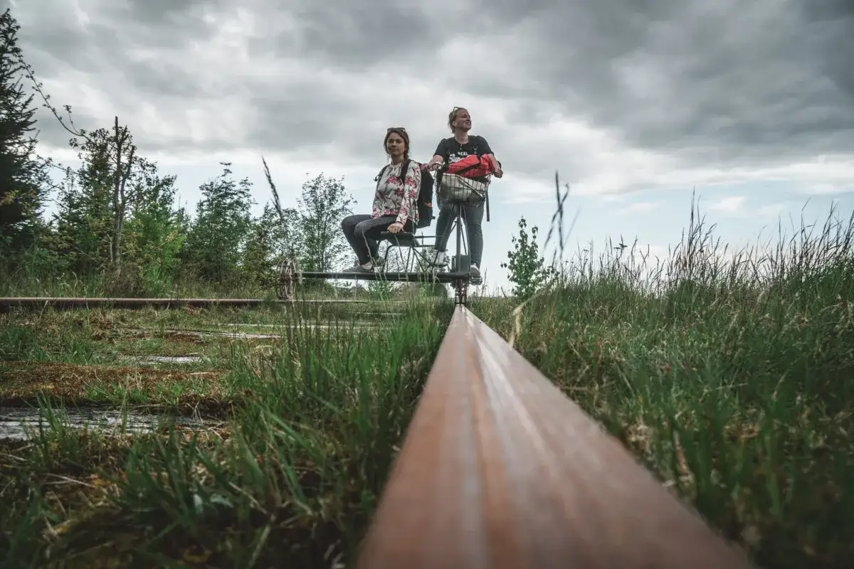 Två personer på en dressin längs en gammal järnväg. En härlig upplevelse för en semester i Sverige med barn.