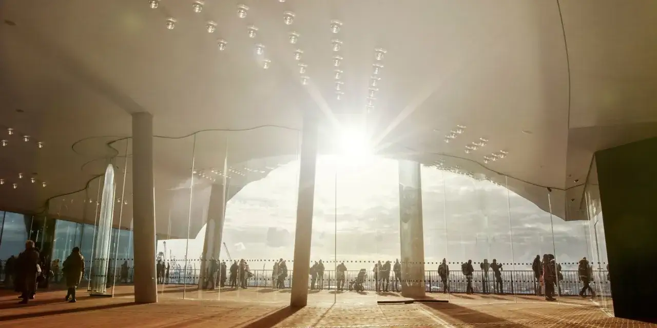 Besökare njuter av utsikten från Elbphilharmonie, konserthus i Hamburg, med solljus som strömmar in genom de stora glasfönstren.