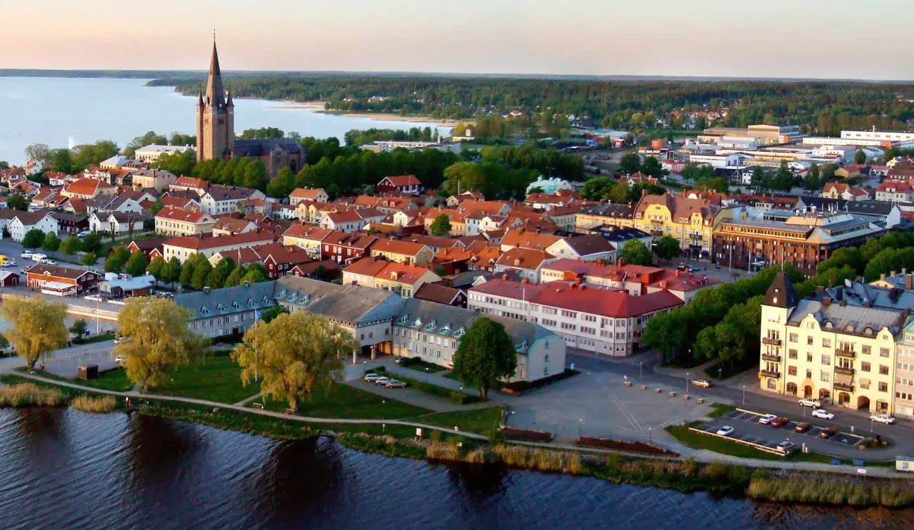 En vy över en stad vid en sjö, med en kyrka med högt torn. Husen har röda tegeltak. Kanske är detta sveriges vackraste stad.