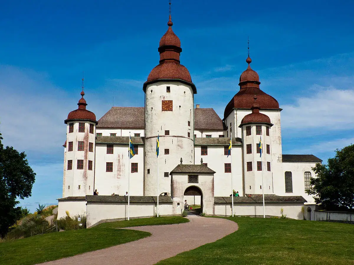 Ett vitt slott med röda tak och svenska flaggor vajande i vinden. En perfekt sommardag i Sverige.