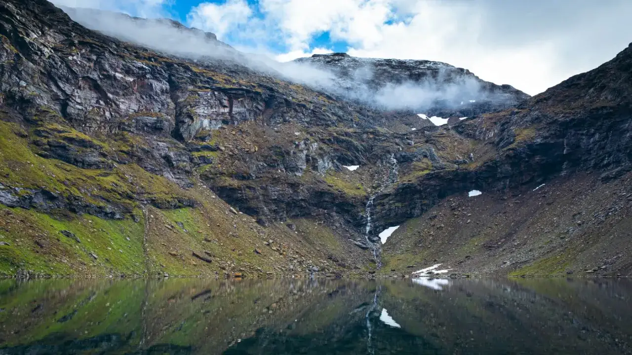 En dramatisk abisko vandring dagstur med en spegelblank sj&ouml; som reflekterar branta, mossbekl&auml;dda bergssluttningar och en forsande vattenfall.